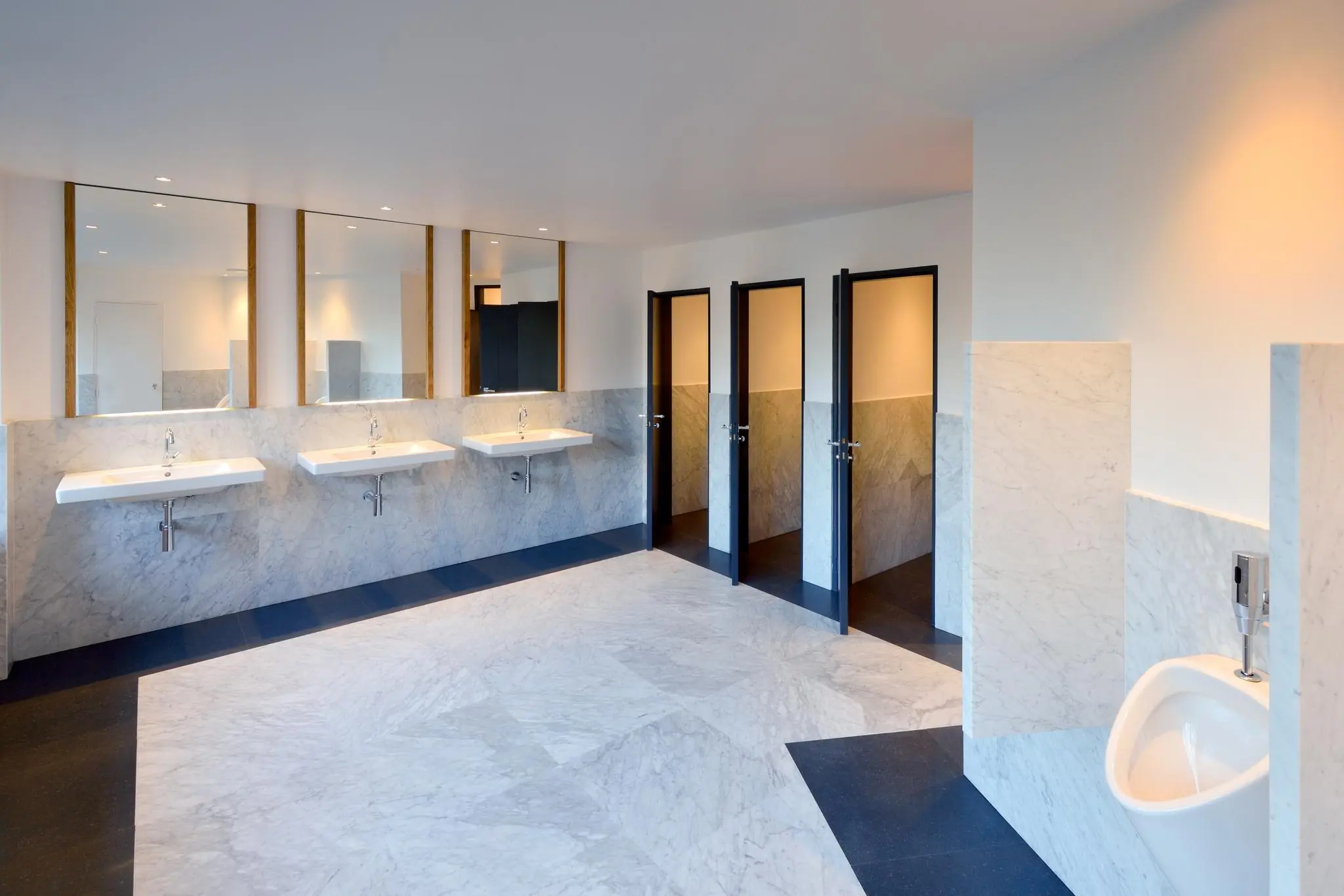 Ruime en modern afgewerkte openbare toiletruimte aan de Floris Grijpstraat met marmeren wanden, meerdere wastafels, toilethokjes en een urinoir.